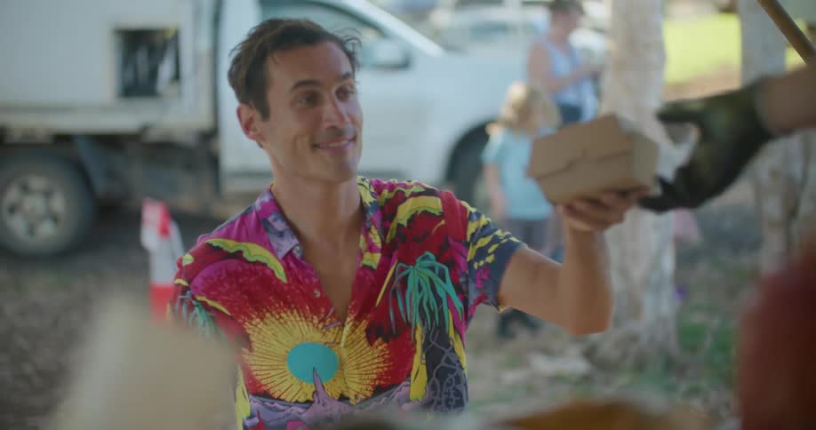 Man with colorful shirt paying for food on a food truck