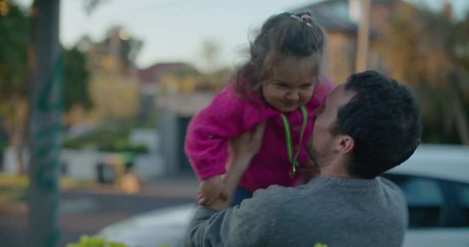 Father picks up daughter and spins around smiling