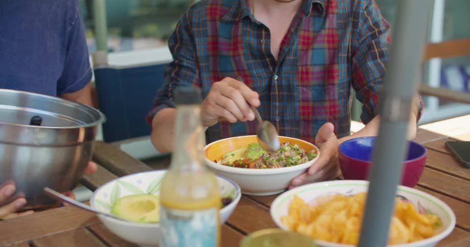 A man divvies up food between him and a friend as they dine outside