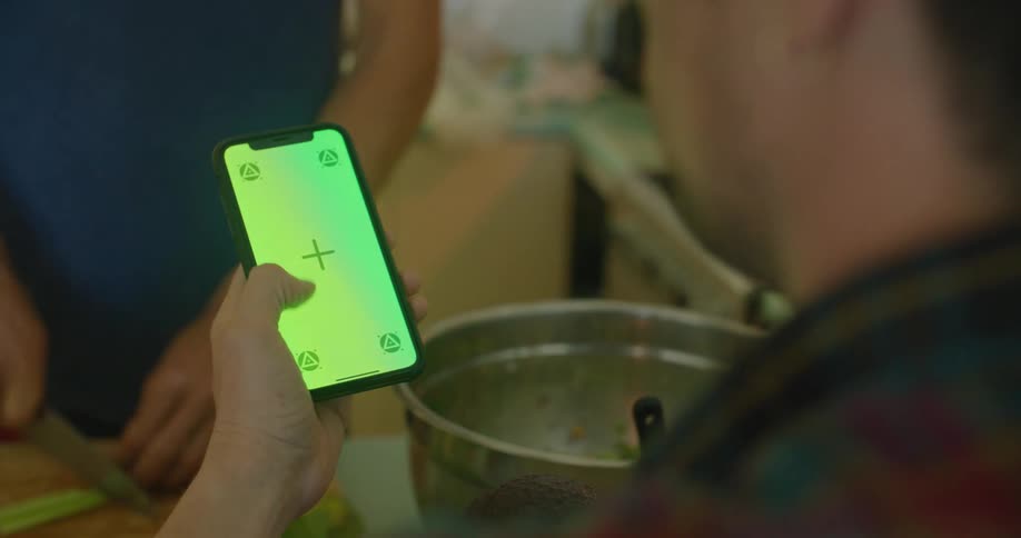 A man swipes an iphone screen in the kitchen