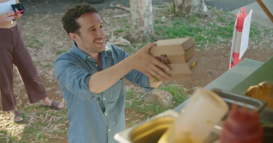A man gets two boxes of food from the food truck