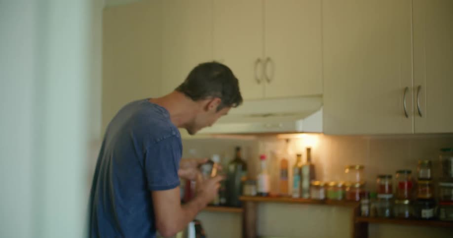 A man adds a spice to a bowl of food hes preparing in a kitchen