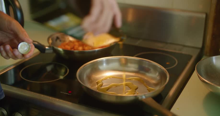 Person spreads olive oil in pan sitting on stove top