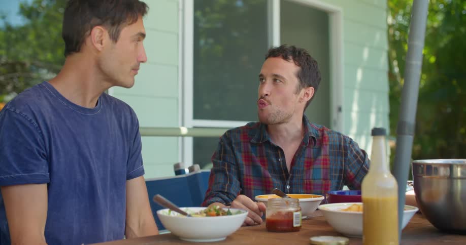 Young male couple sharing a meal on the porch at home
