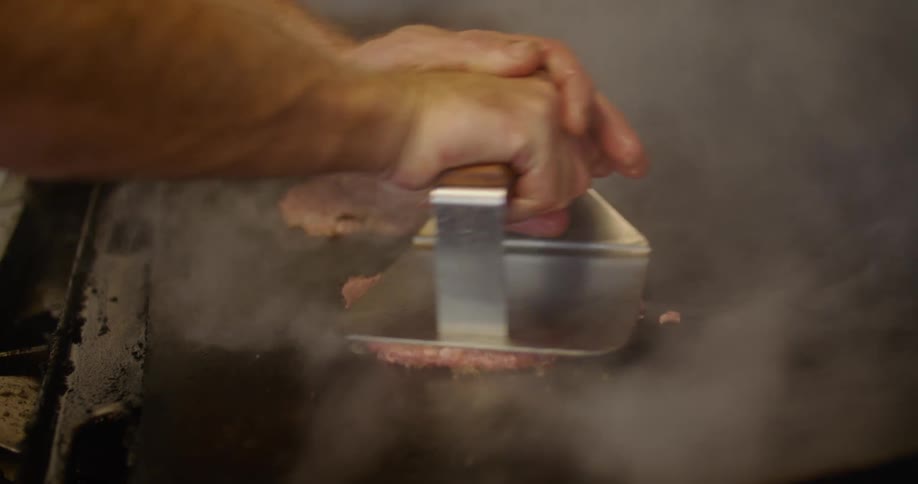 Young man cooking grilled hamburgers on a restaurant