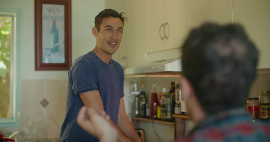 Man cooking food while talking to a friend in the kitchen at home