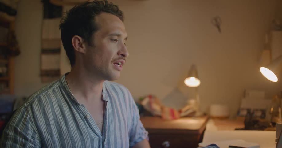A man holds up a piece of fabric and discusses it during a video call on a laptop