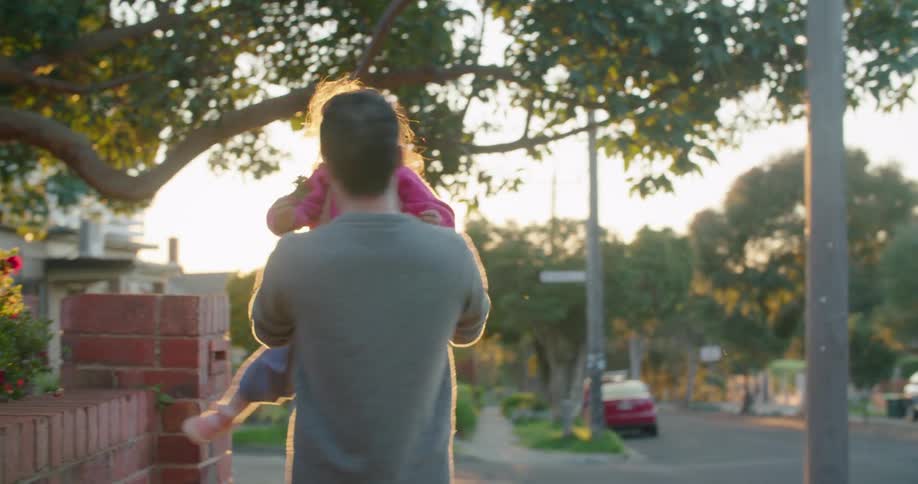 Father playing with her daughter in the neighborhood at sunset