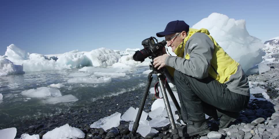 A man uses a camera and tripod to take pictures