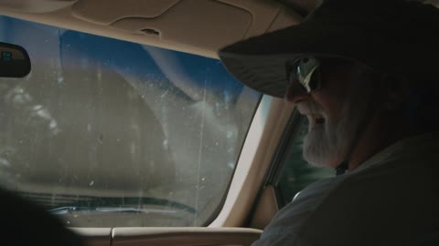 A man in a hat is a passenger in a car