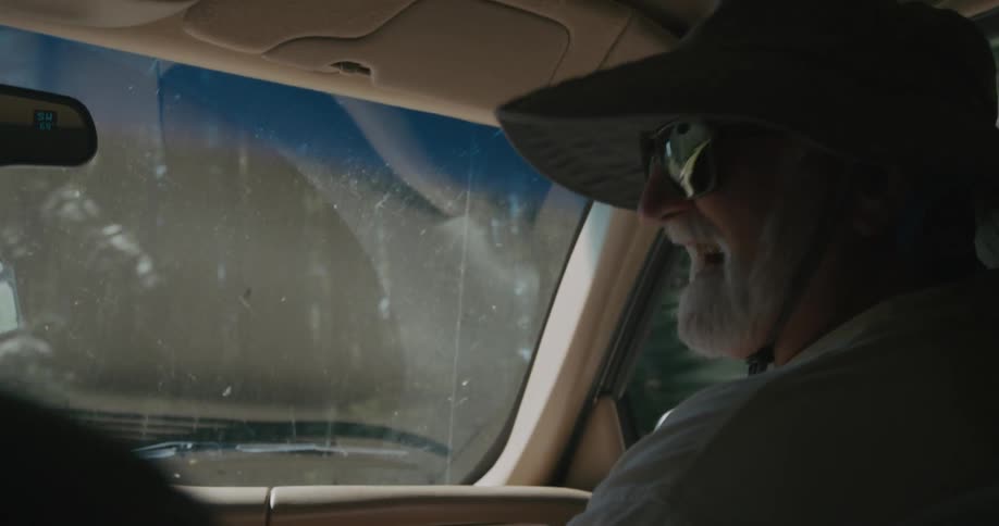 A man in a hat is a passenger in a car