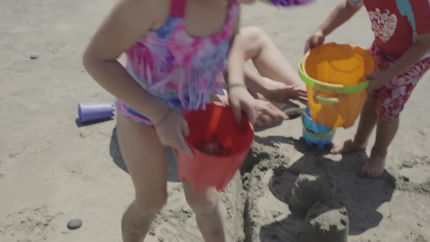 Children carry buckets and dump the water in the sand