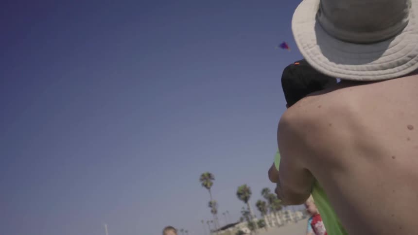 A man is helping a child fly a kite in a clear sky
