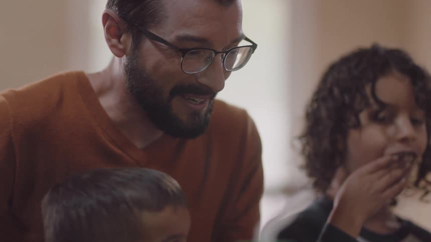 A father and his sons are eating food in a room
