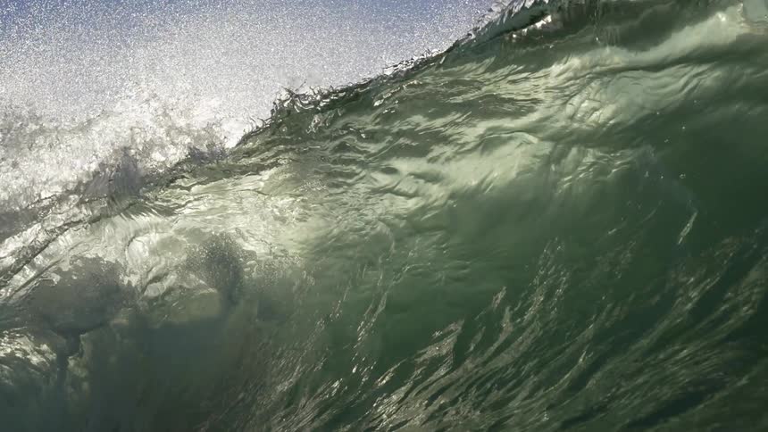 Wave rolls in splashing as it moves overhead