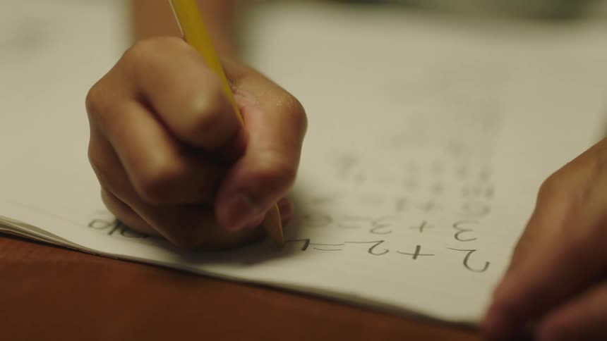 Girl doing her math homework with pencil over paper