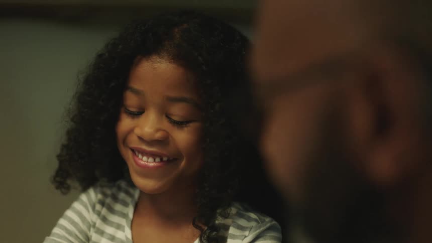 A young girl laughs while sitting at a table with her father