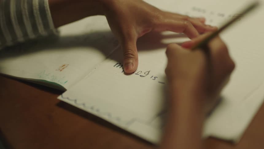 A child is doing homework on a piece of paper