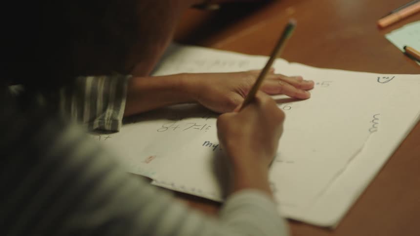 A girl is doing math homework with a pencil