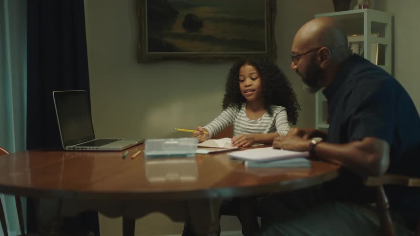 A man helps his daughter do homework