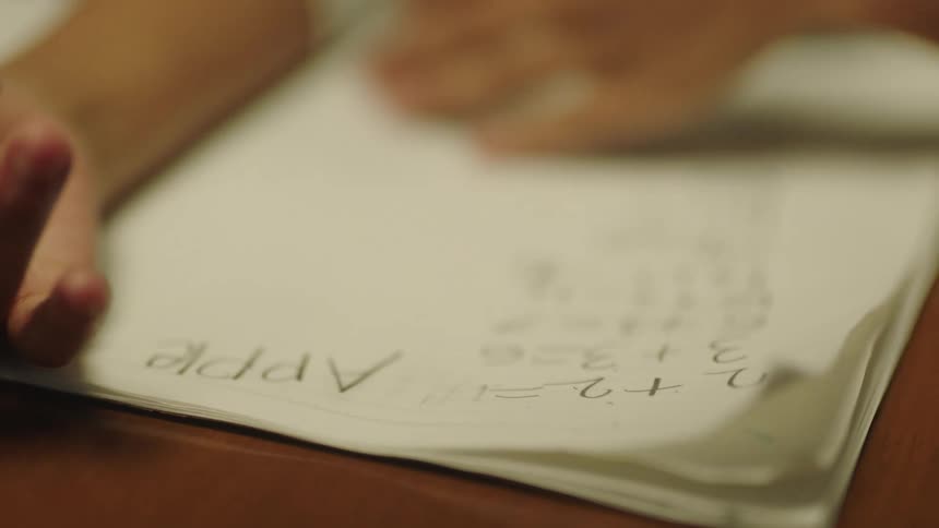 Female student writes down in notebook erasing and cleaning the paper