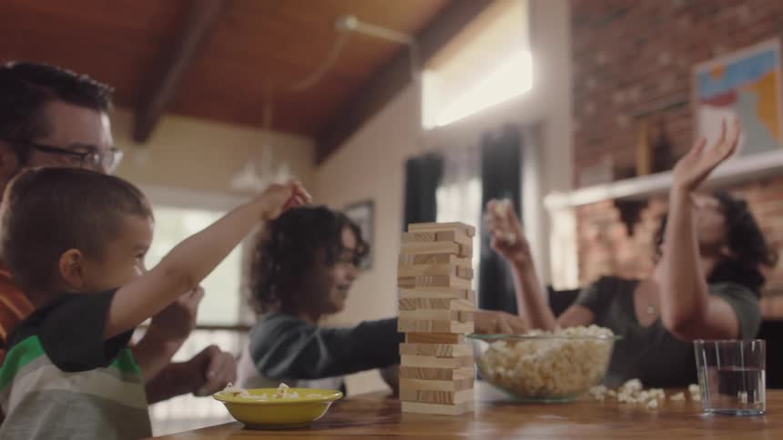 Happy family playing with popcorn sitting in the dinning table at home