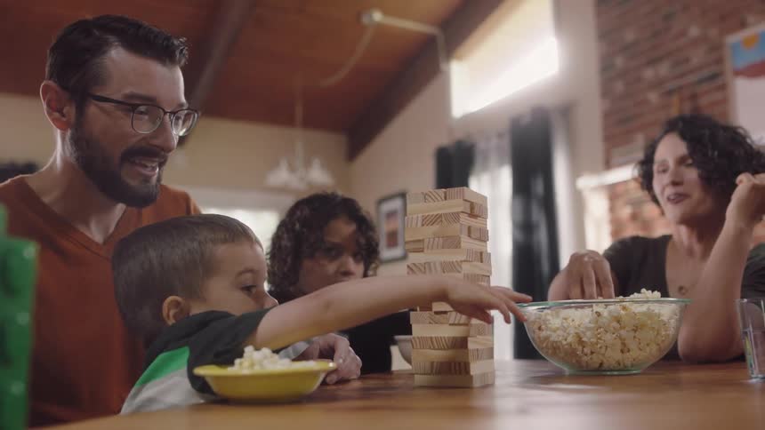 A family of four eat popcorn as they play a block stacking game at home