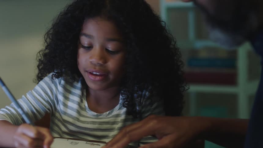 Man helps girl with curly hair work on her homework