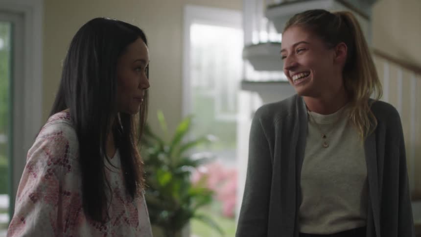 Two young women laugh as they chat at home