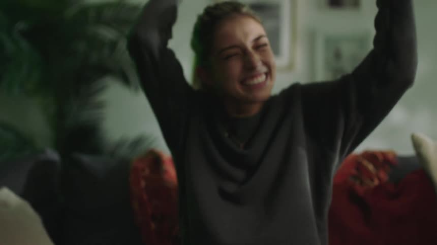 Happy young woman playing video games on the couch at home celebrates
