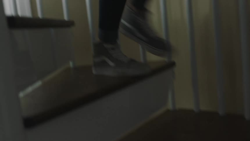 Woman wearing sneakers walking down a spiral staircase at home