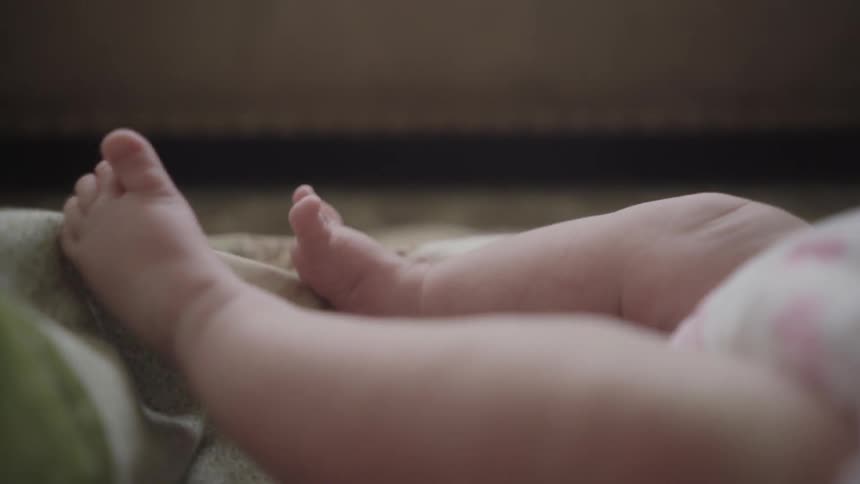 A babies legs kick around in a bed