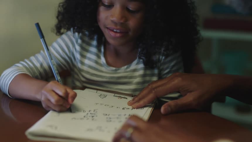 A father gives a fist bump to his daughter for completing a math problem