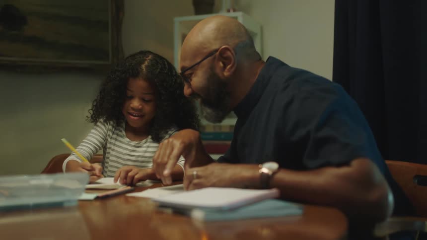 A man helps his daughter with homework and gives her a high five