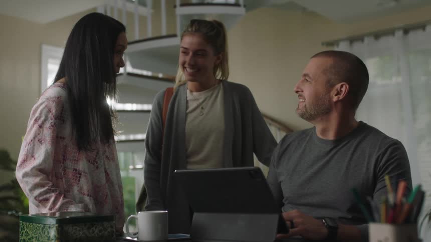 A man is talking with two women at his desk
