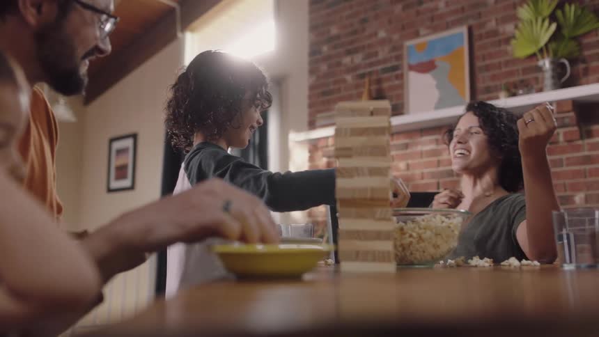 A family sit at the table playing and throwing popcorn