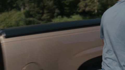 Smiling man gets out of truck and opens the truck bed cover