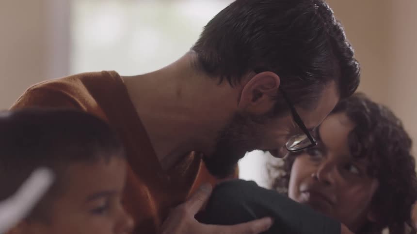 Man with glasses beard and orange sweater plays jenga with kids
