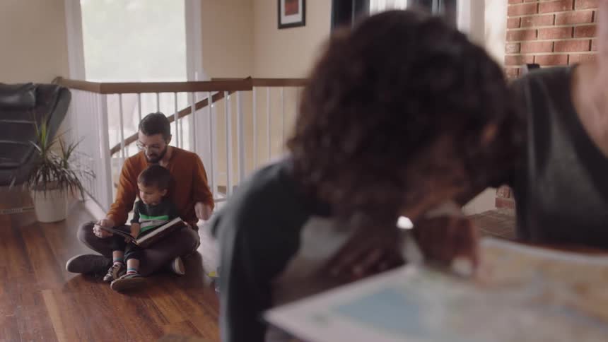 Parents helping their children with homework in the living room of a house