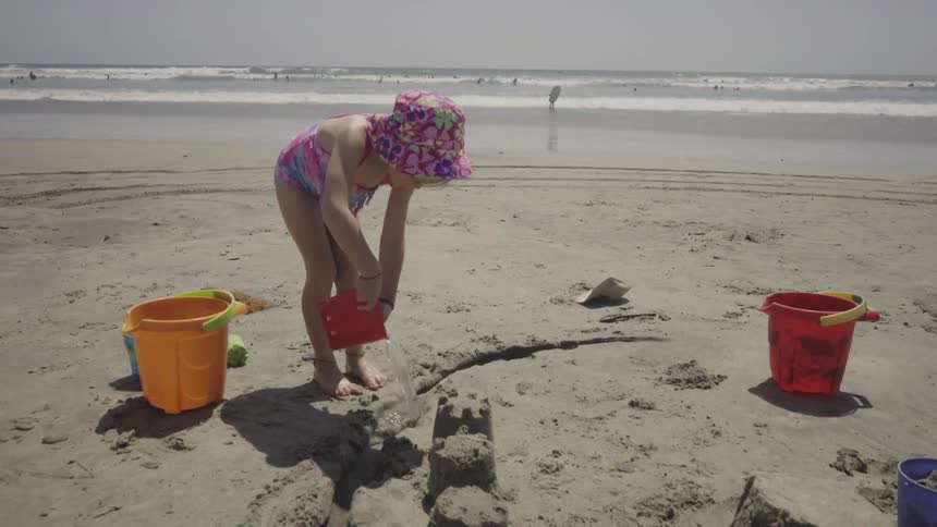Child playing with water and sand on the beach