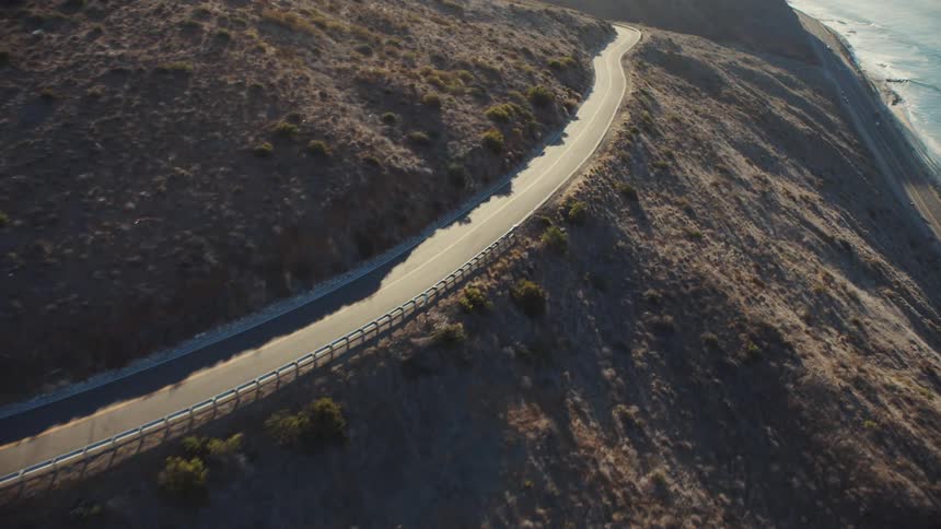 An aerial view of a road in the hills along the coast