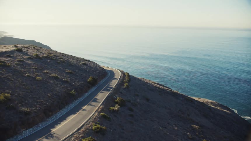 Aerial view of coastal mountain road overlooking a blue sea