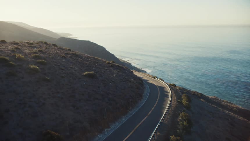 Aerial view of a road winding around a coastal mountain