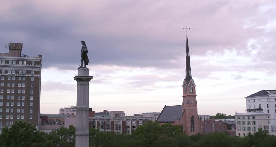 Aerial view of a statue over a column near a church on the city skyline at evening