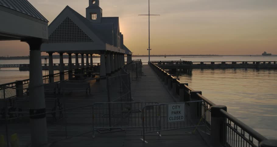 The golden sun reflects off the rippling water surface near an empty pier