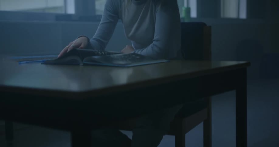 A teenage girl sits a desk and reads