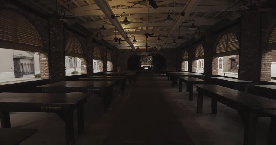 Long room with tables lined up along the sides next to windows and fans on the ceiling