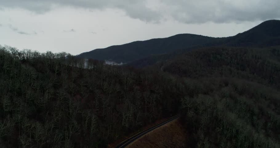 An aerial view of hills and a road going through the forest