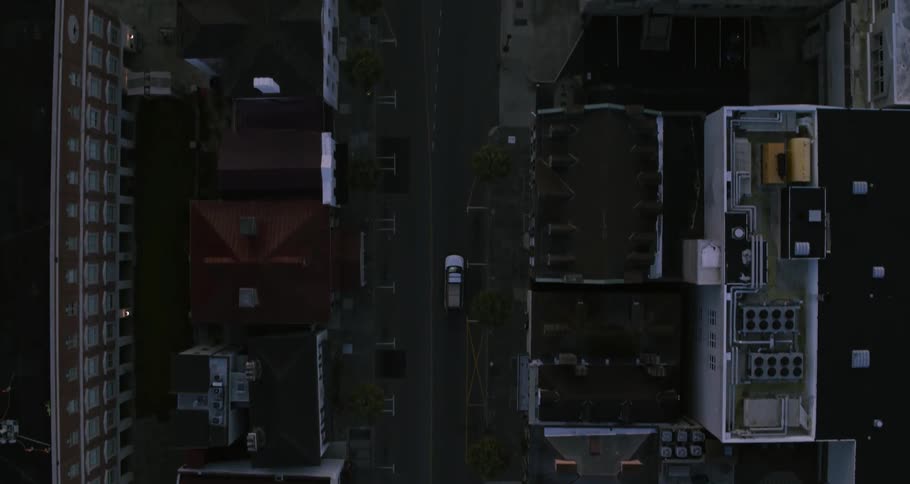 A car is traveling on a city street in between many buildings