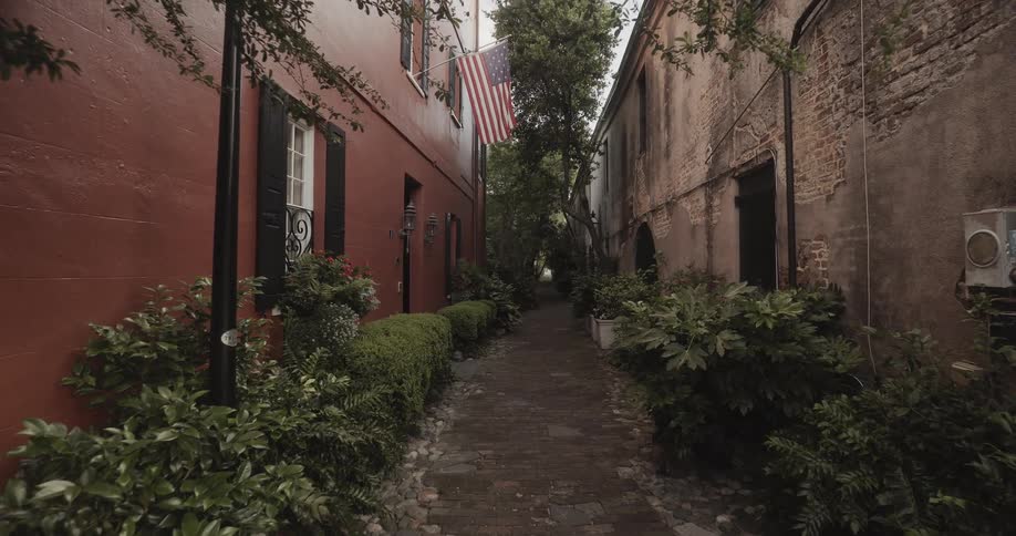 The narrow alley has a flag hanging from a window